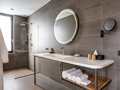 Luxe en ruime badkamer van een Junior Suite met aparte regendouche, speaker, en een lichtgevende spiegel in Notiz Hotel Leeuwarden. 